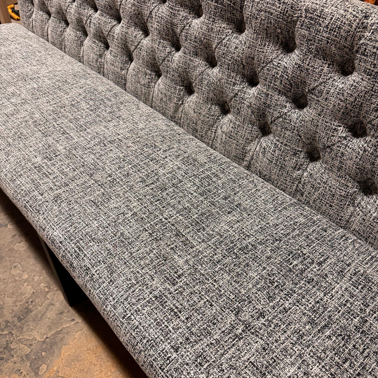 Gray tufted sofa with a textured fabric finish.