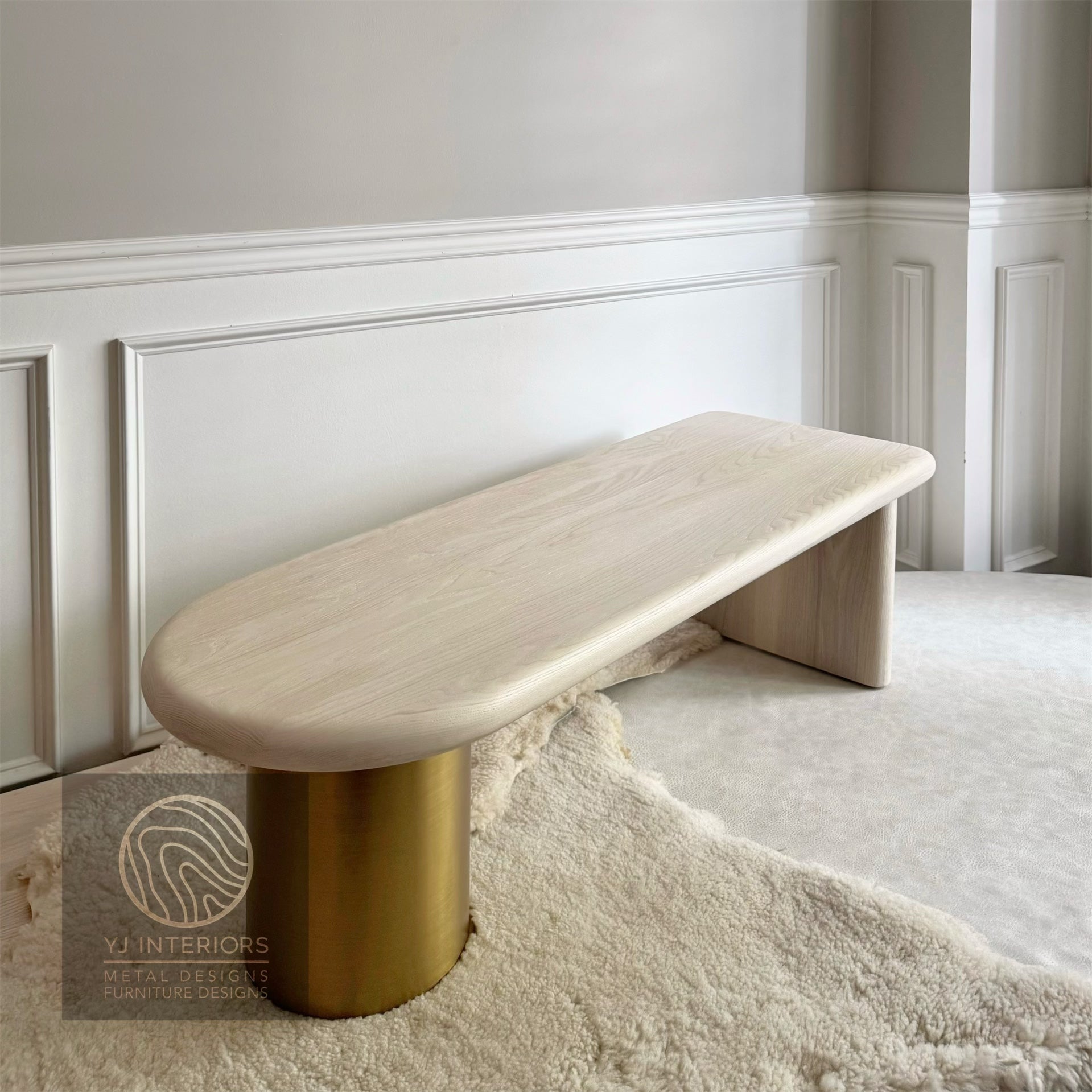 Modern bench with gold cylindrical base against a white wall