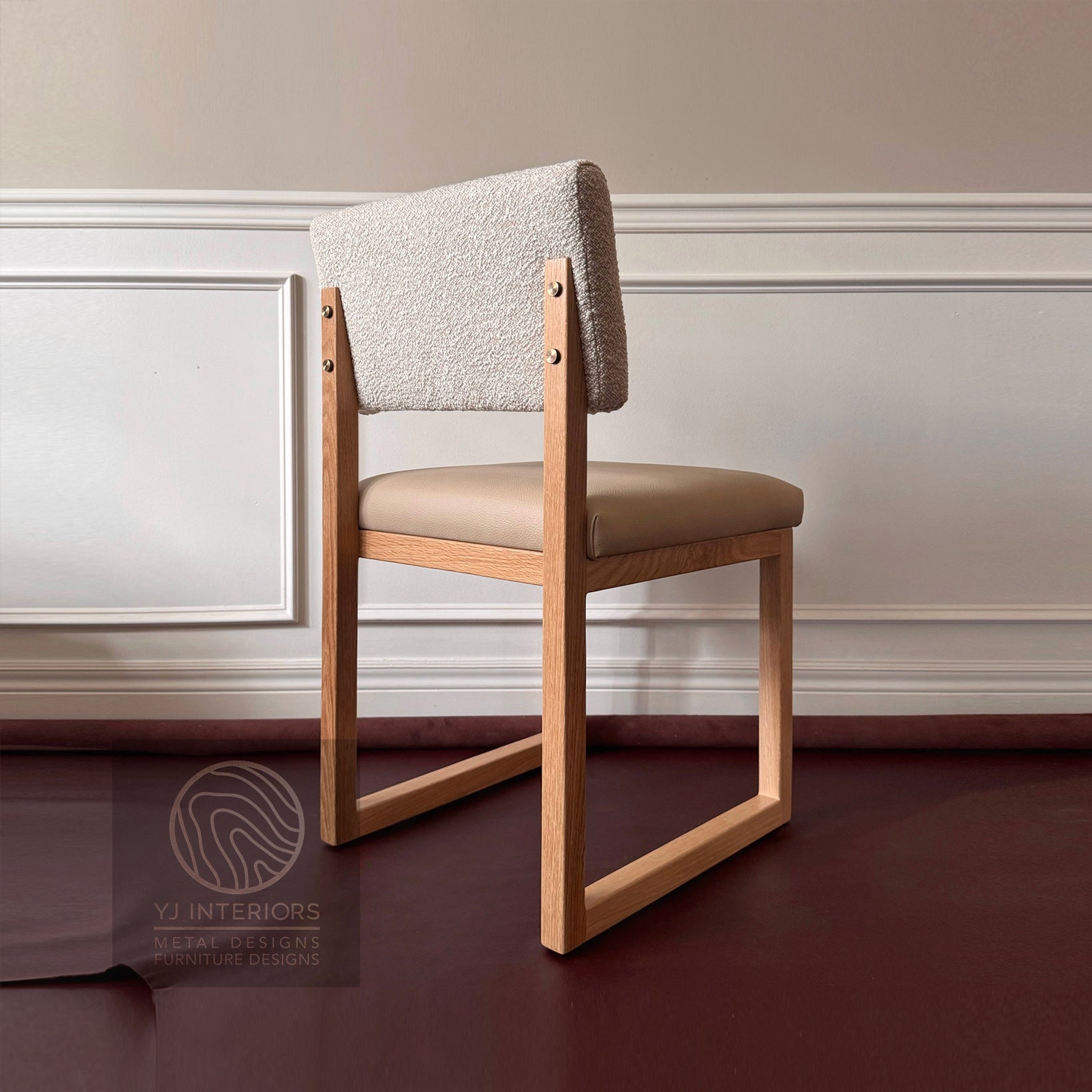 Chair with wooden frame and upholstered seat and backrest against a neutral wall.