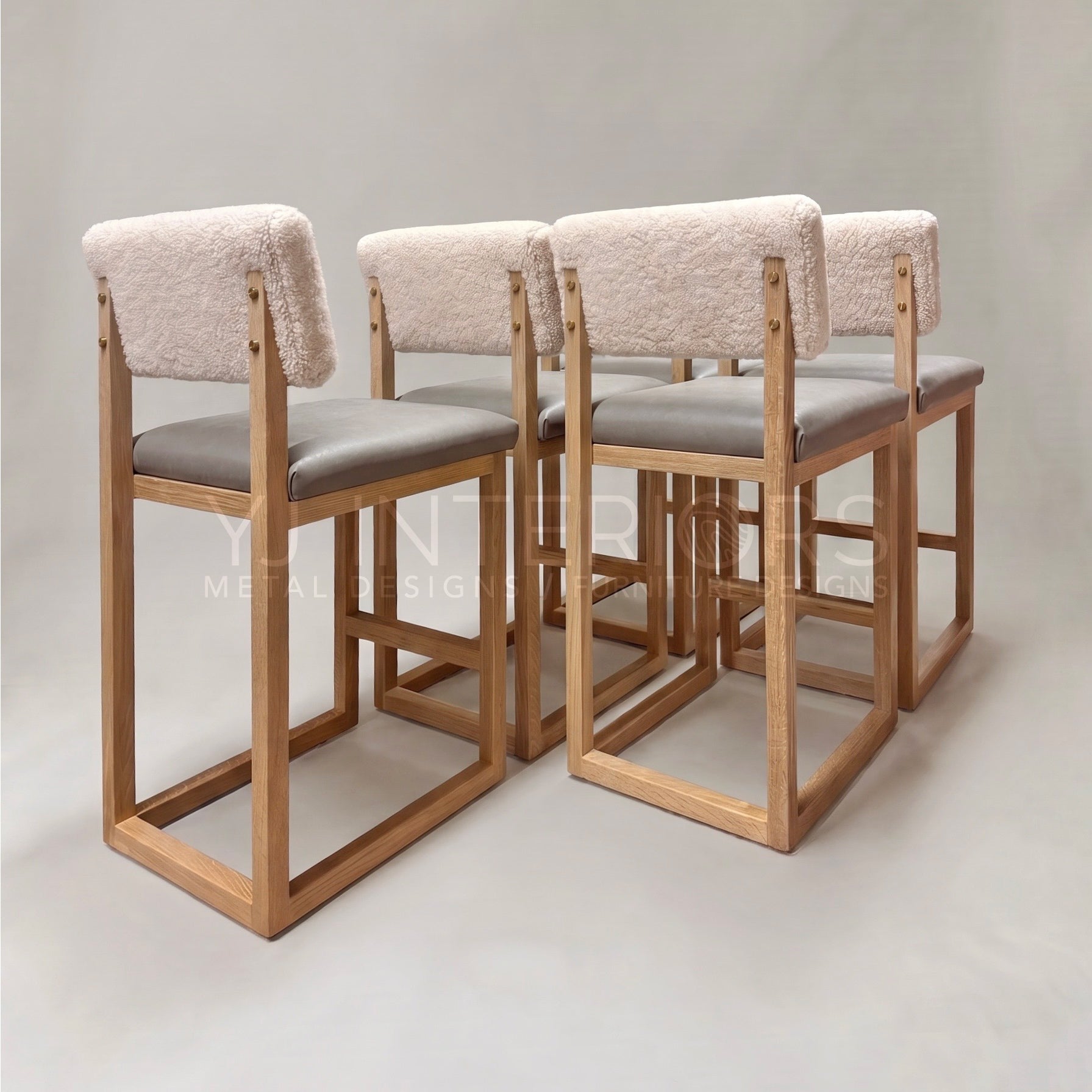 Four wooden bar stools with light beige bouclé backs and gray upholstered seats, arranged in a row against a neutral studio background.