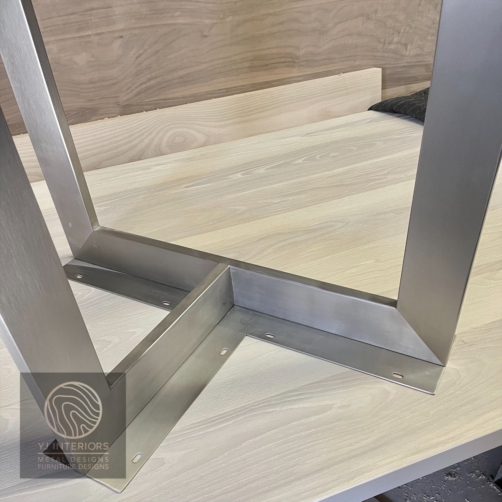 Metal table legs on a wooden floor with a visible brand logo.