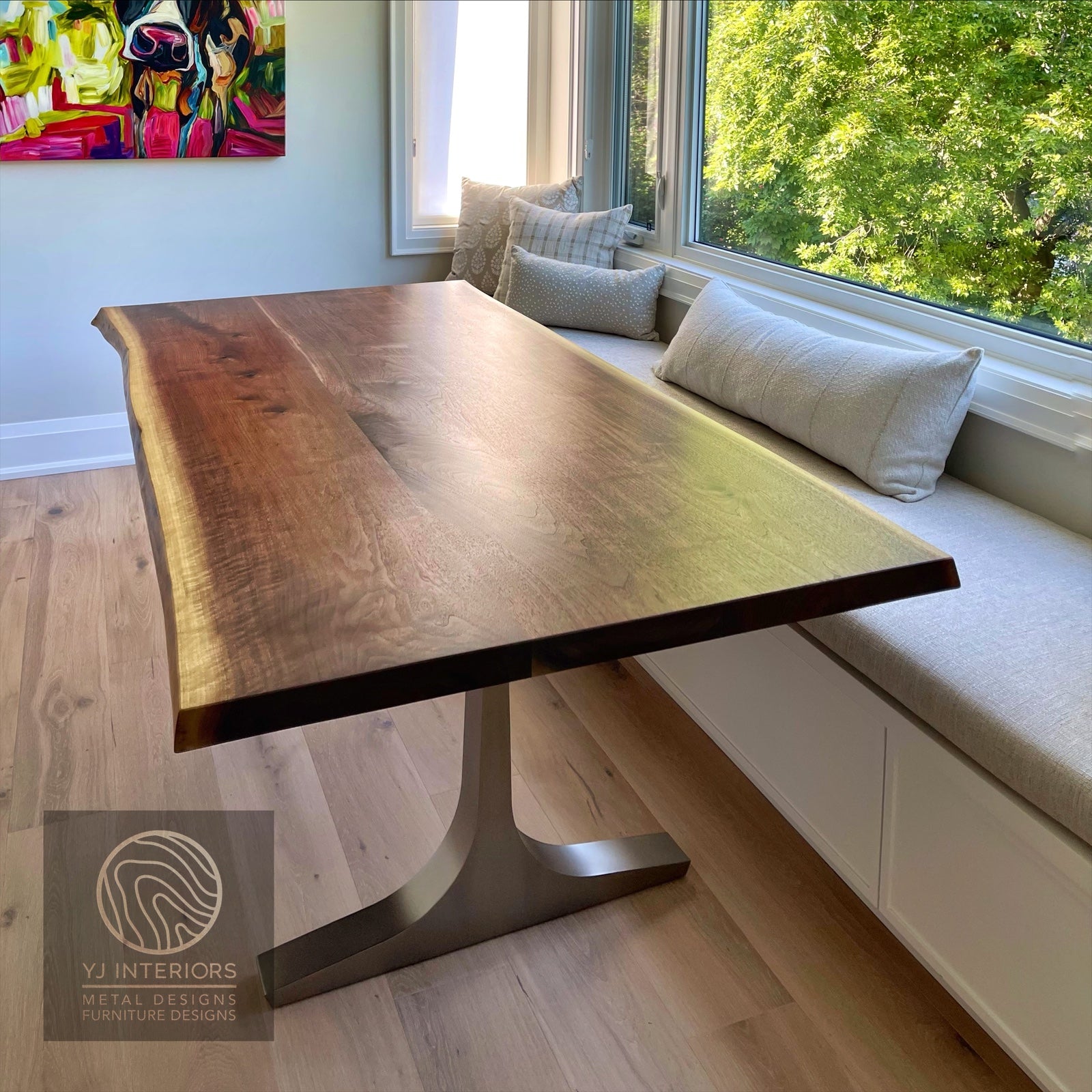 Wooden dining table in a room with a window seat and greenery outside