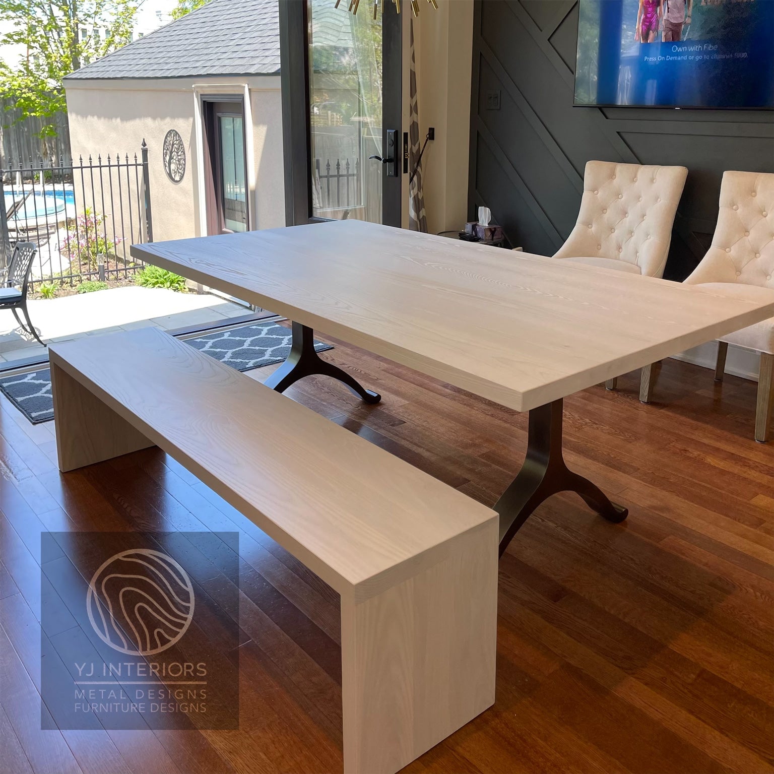 Wooden dining table with bench and chairs in a room with a pool view.