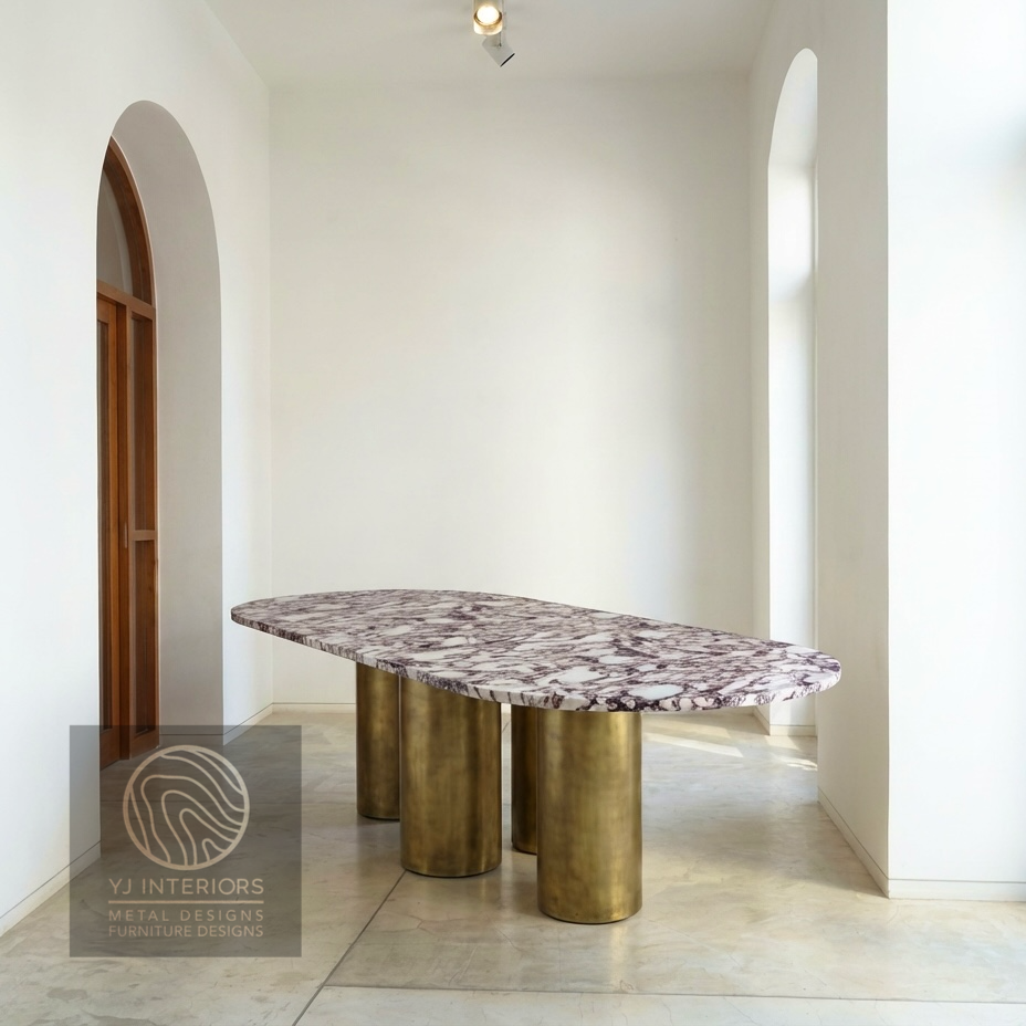 Close-up of the brushed antique brass finish on a round metal table leg. The texture shows a soft, muted gold luster with a vintage patina, highlighting the high-quality metalwork.