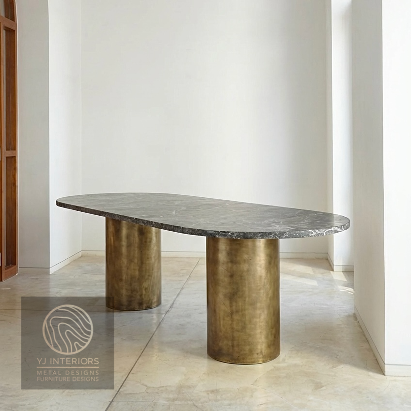 Close-up of the brushed antique brass finish on a round metal table leg. The texture shows a soft, muted gold luster with a vintage patina, highlighting the high-quality metalwork.